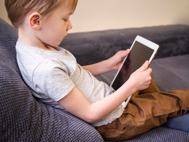 Free photo little boy playing on a tablet