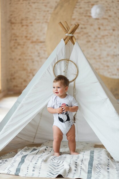 little boy playing in a tent in loft interior with brick wall.