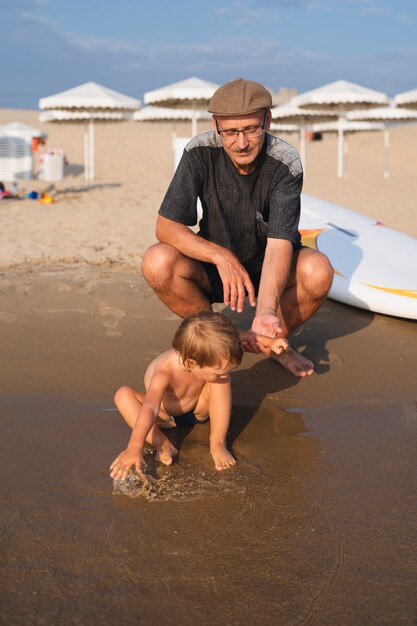 おじいちゃんの横で水で遊ぶ少年