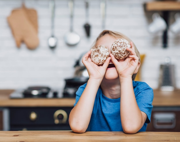 Foto gratuita ragazzino che gioca con i biscotti