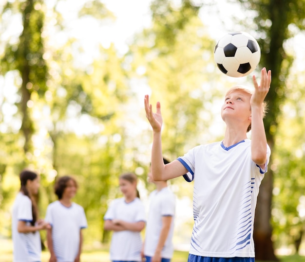 Foto gratuita ragazzino che gioca con un calcio all'esterno