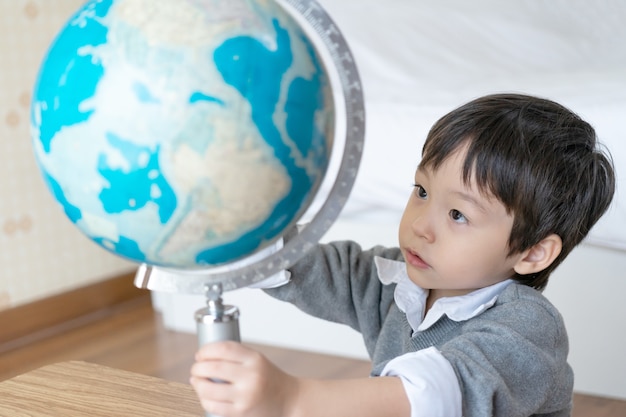 Little boy playing with globe at home