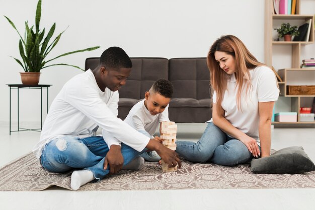 Little boy playing wooden tower game with his parents