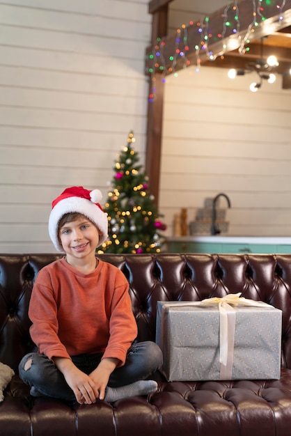 Маленький мальчик позирует рядом с рождественским подарком
