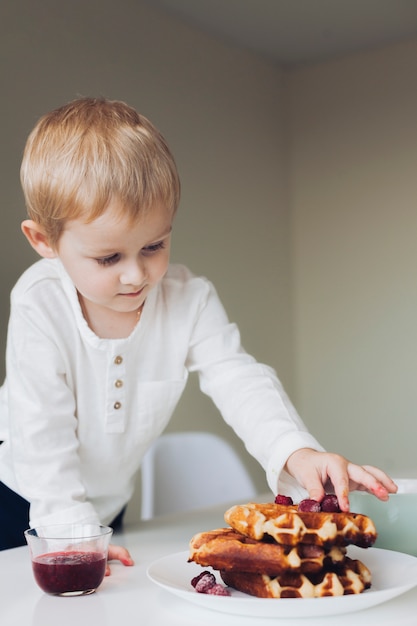 Little boy putting fruit on waffle