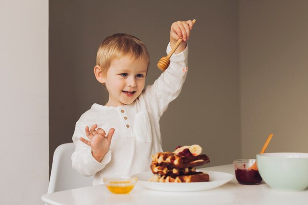 ワッフルに蜂蜜を入れて小さな男の子