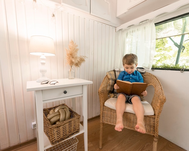 Little boy reading a book while sitting on an armchair