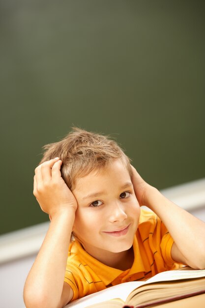 Little boy reading and daydreaming in class