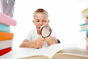 Бесплатное фото Маленький мальчик, чтение с увеличительным стеклом