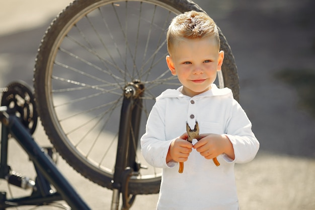 Foto gratuita il ragazzino ripara la sua bici in un parco