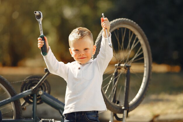 小さな男の子は公園で彼の自転車を修理します