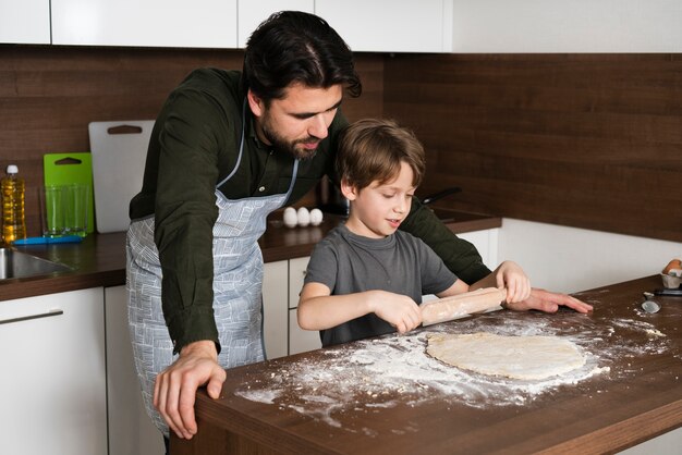 Little boy rolling dough at home