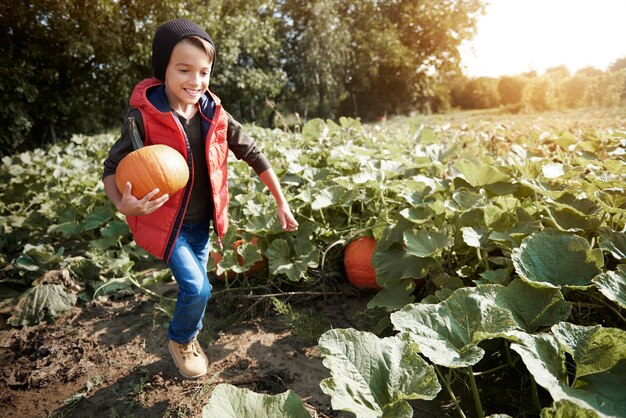 Little boy running with a pumpkin on the field