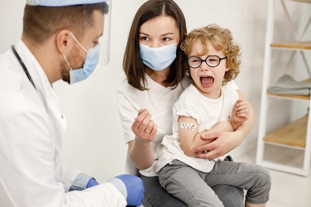 Маленький мальчик кричит, потому что доктор сделал прививку