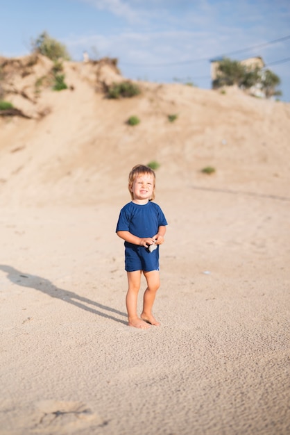 ビーチの上を歩く海辺で小さな男の子