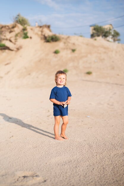 Little boy at seaside walking on beach