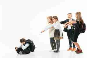 Free photo little boy sitting alone on floor and suffering an act of bullying while children mocking