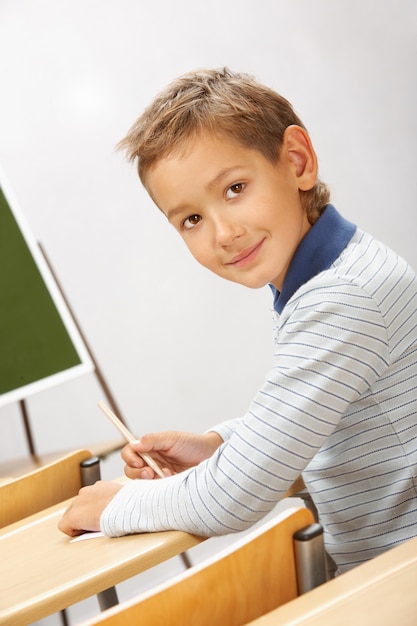 Бесплатное фото Маленький мальчик сидит в одиночестве в своем классе