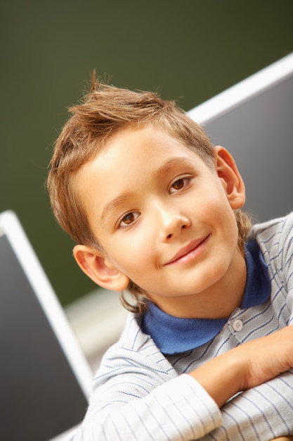 Foto gratuita ragazzino che si siede in aula e sorridente