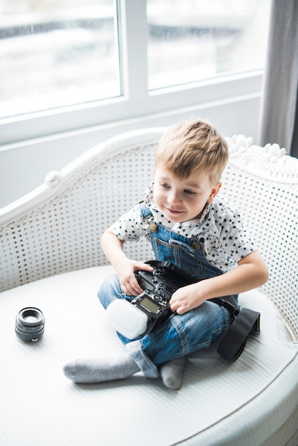 Little boy sitting with camera on sofa 