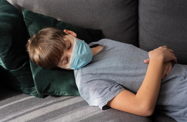 Little boy sleeping with a medical mask on