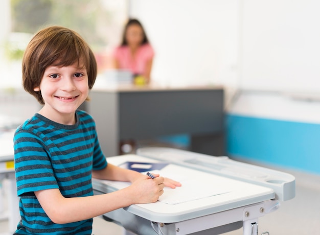 Little boy smiling while sitting at his desk