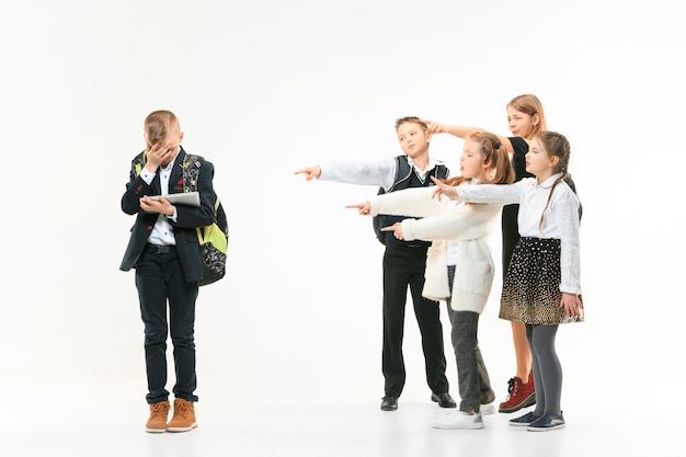 Free photo little boy standing alone and suffering an act of bullying while children mocking