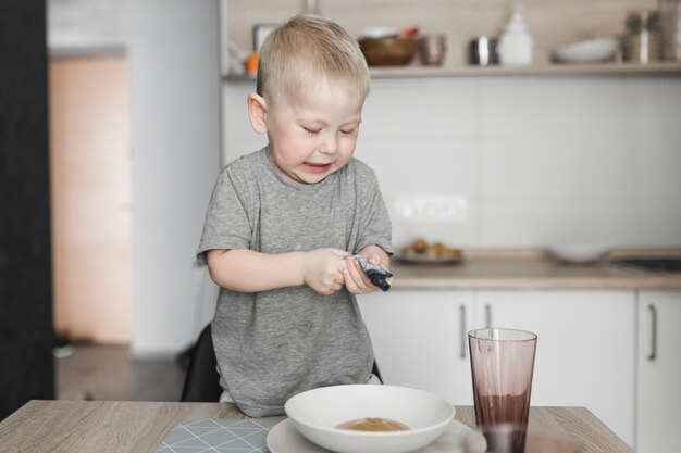 ボウルの中のパケットを握っている椅子に立っている小さな男の子