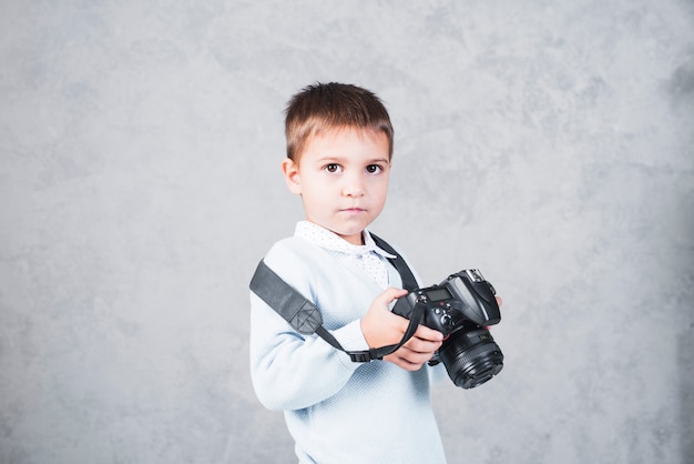 Little boy standing with camera