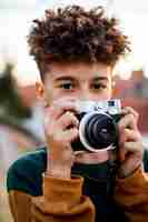 Free photo little boy taking a photo with his camera outside