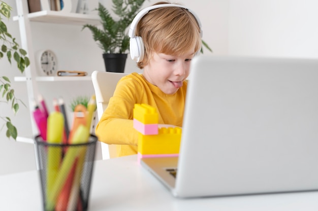 Little boy using laptop and headphones at home