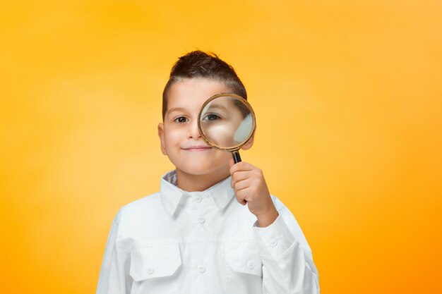 Little boy using magnifier looking close up