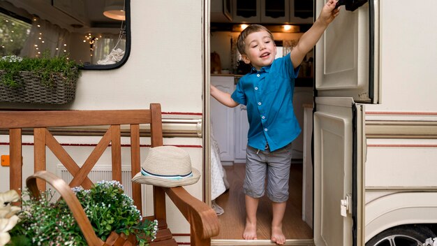 Little boy wanting to close the door of a caravan