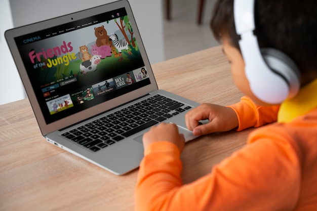 Free photo little boy watching films on laptop