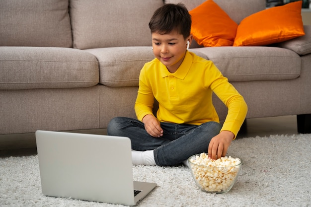 Free photo little boy watching films on laptop