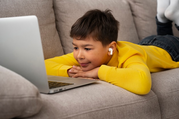 Free photo little boy watching films on laptop