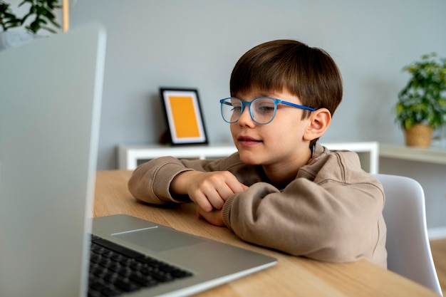 Free photo little boy watching films on the laptop