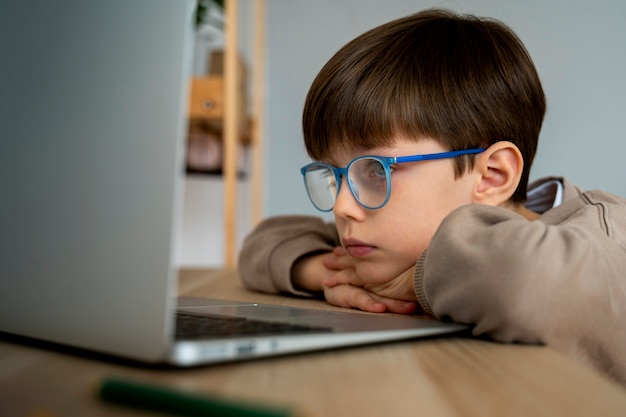 Free photo little boy watching films on the laptop