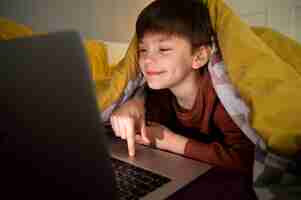 Free photo little boy watching films on the laptop