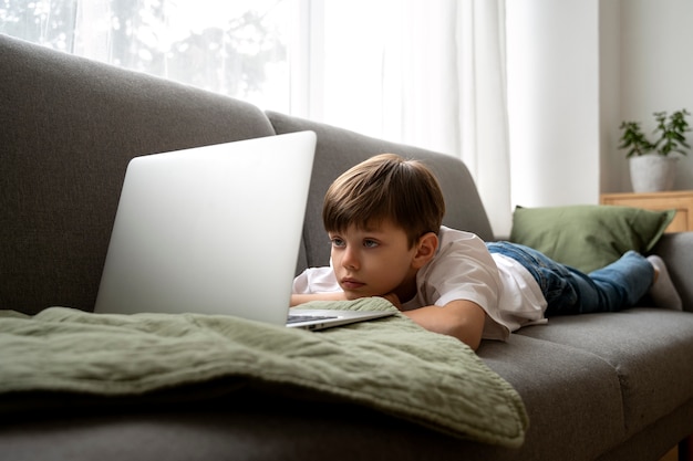 Бесплатное фото Маленький мальчик смотрит фильмы на ноутбуке