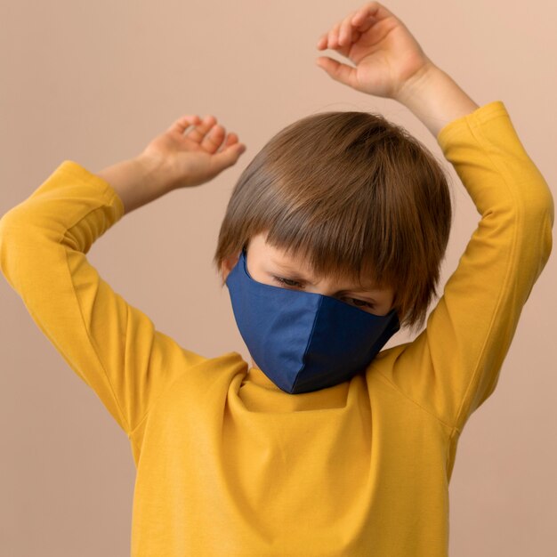 Little boy wearing a medical mask indoors