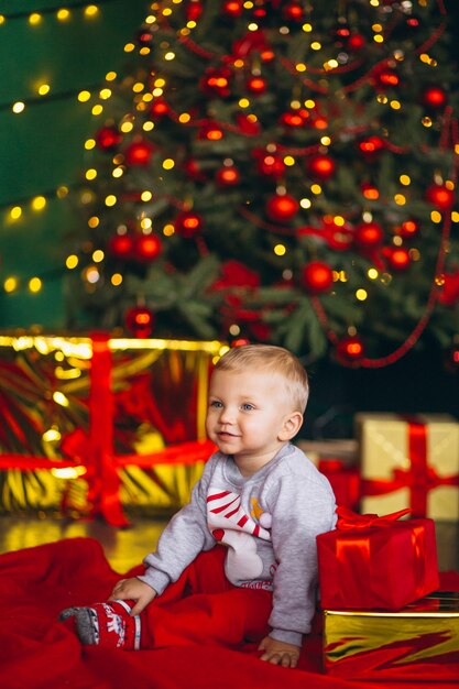 Chriostmasツリーによるクリスマスプレゼントと小さな男の子