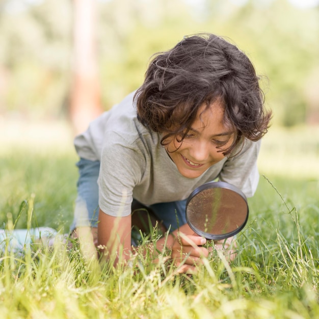 屋外の拡大鏡を持った少年