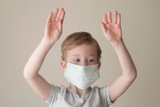 Free photo little boy with mask and raised hands