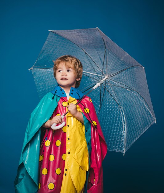 Little boy with rainbowcolored umbrella isolated on blue background cloud rain umbrella raining conc...