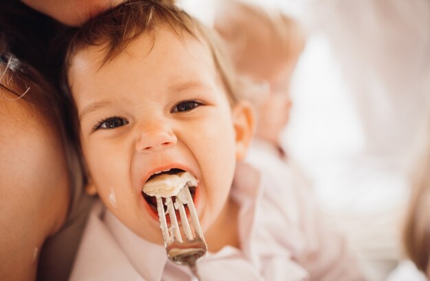 小さな男の子が両親の腕に座って何かを食べる