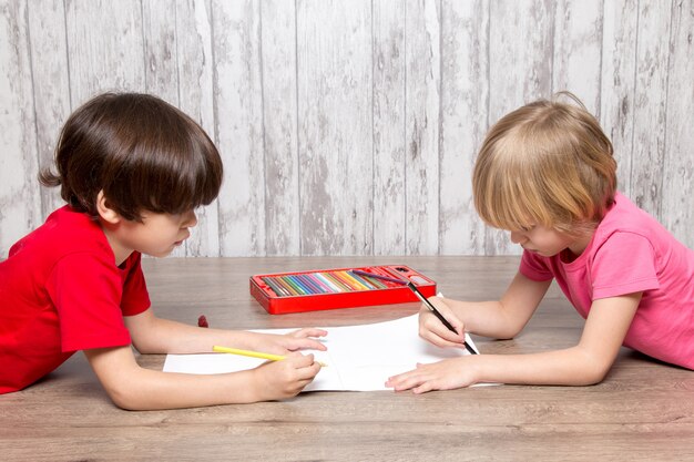 Little boys in pink and red t-shirts drawing