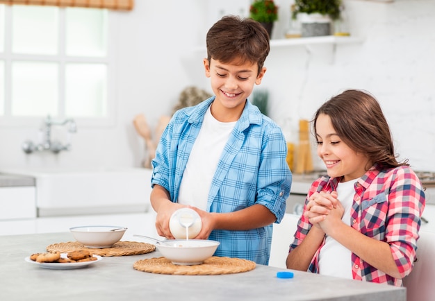 Little brother helping sister on breakfast