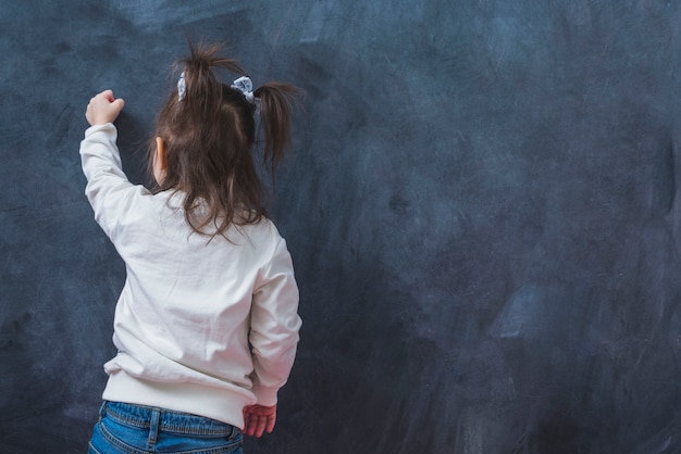 Little brunette girl writing on wall