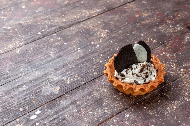 little cake with cream and chocolate cookies isolated on wooden brown desk, cake biscuitt bake color